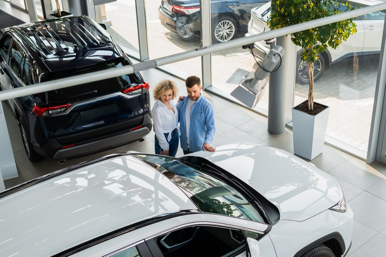Zwei Personen betrachten einen weißen Wagen im Verkaufsraum eines Autohauses