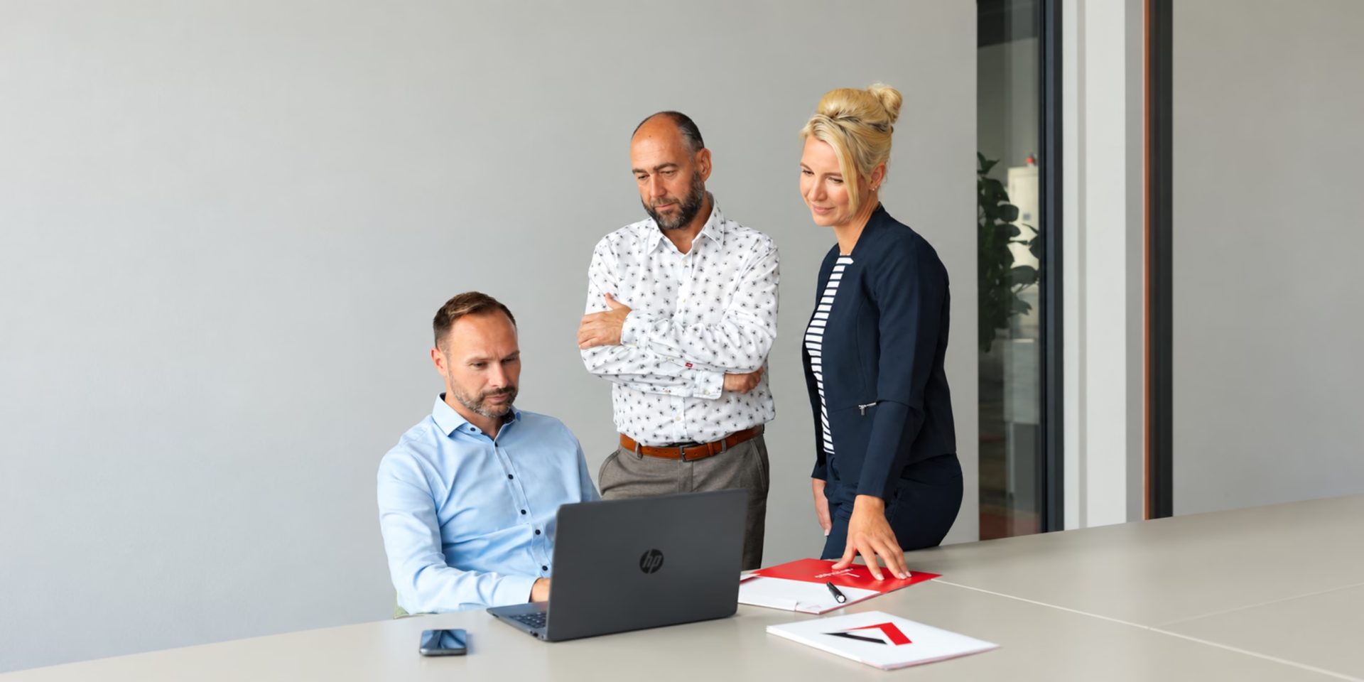 Drei Mitglieder des advandas-Teams besprechen gemeinsam ein Projekt am Laptop im Büro