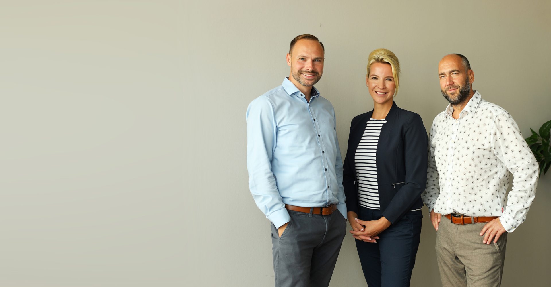 Drei Mitglieder des advandas-Teams stehen vor einer hellen Wand neben einer Zimmerpflanze